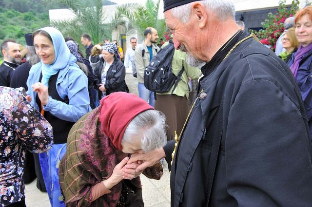 Паломница Валентина из города Зеленограда берет благословение у священника сербской группы паломников